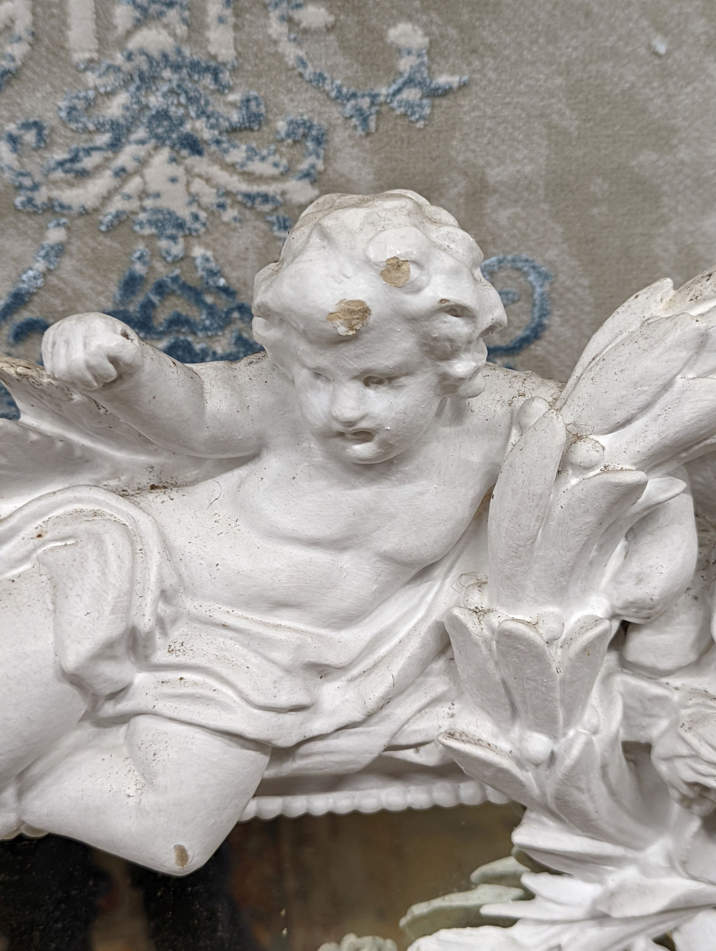 An Edwardian carved wood and gesso overmantel with cherub surmount, later painted white, width 188cm, height 96cm and a two white painted door pediments in need of restoration